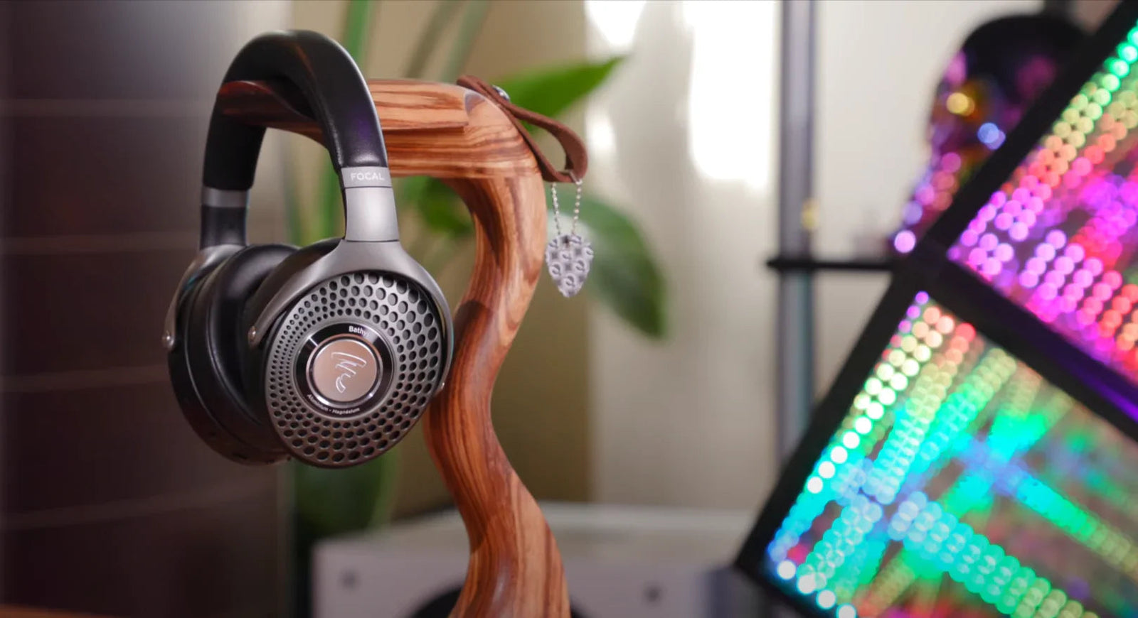Focal Bathys Bluetooth wireless headphones on wooden stand with LED lights in background