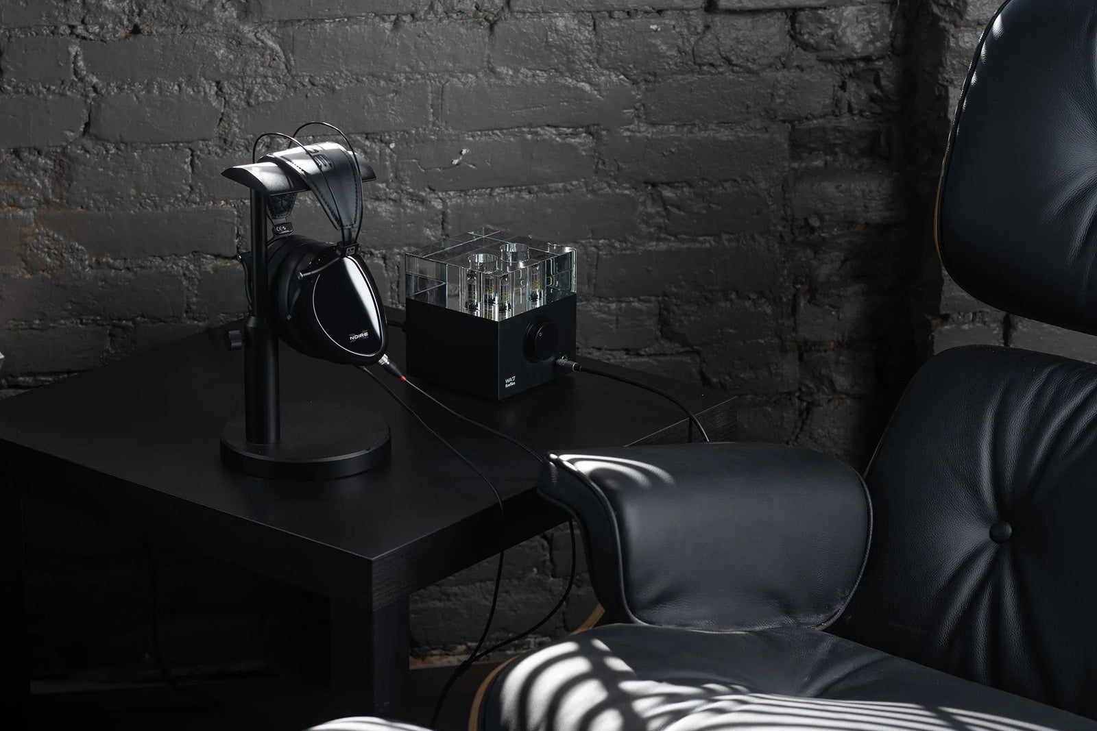 High-end headphones on stand with tube amplifier on black table, modern audio setup The Source AV